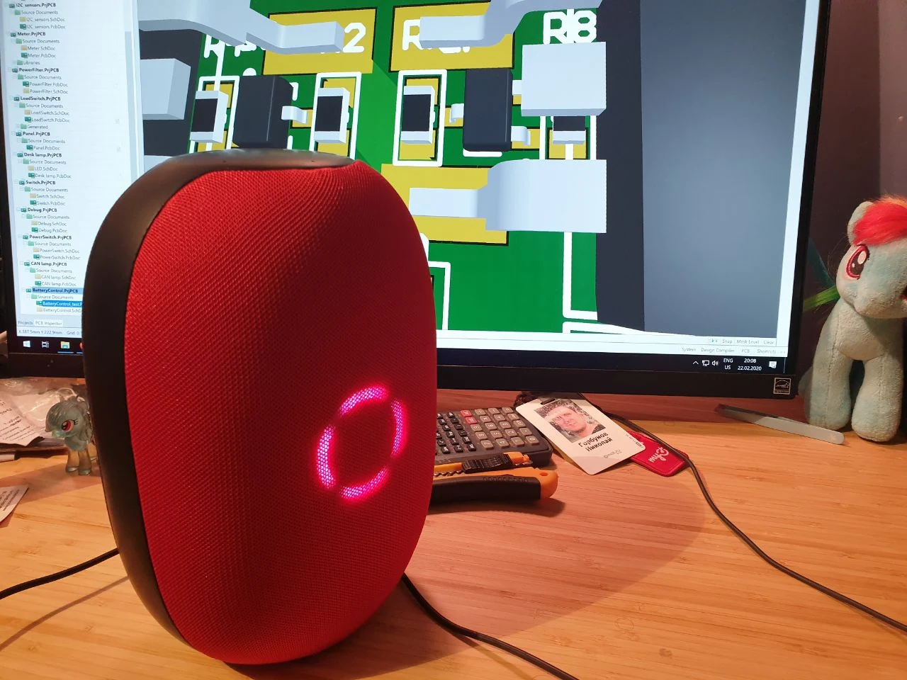 Red Capsula prototype in front of the Altium PCB design